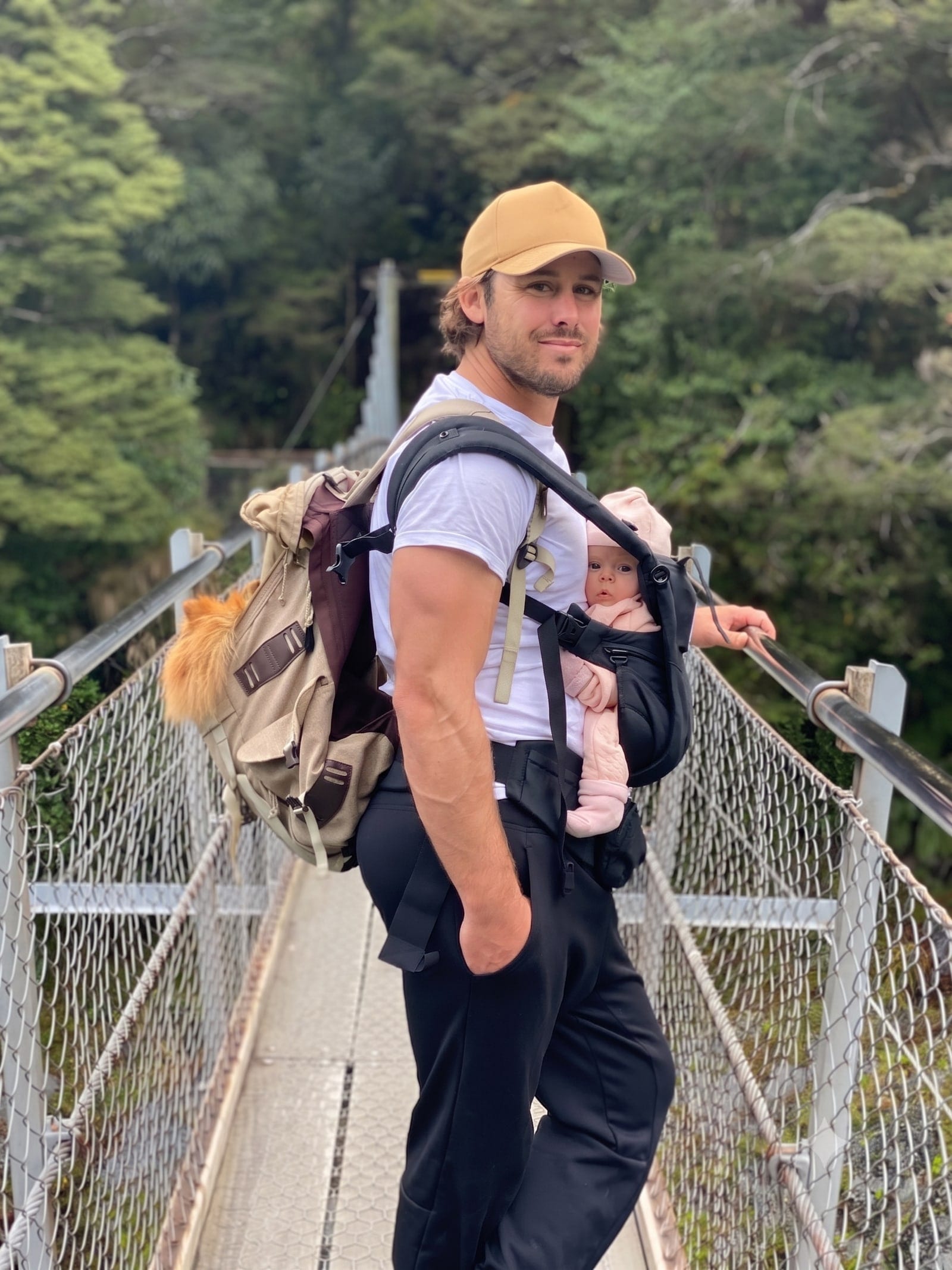 Jesse, Mountain Vogue's driver, crossing a Fiordland swing bridge with his infant in a front carrier.